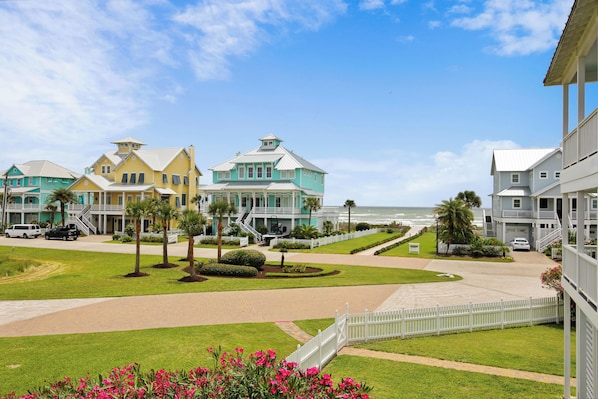 A coastal hotel with multiple buildings, a paved walkway, and a view of the ocean.