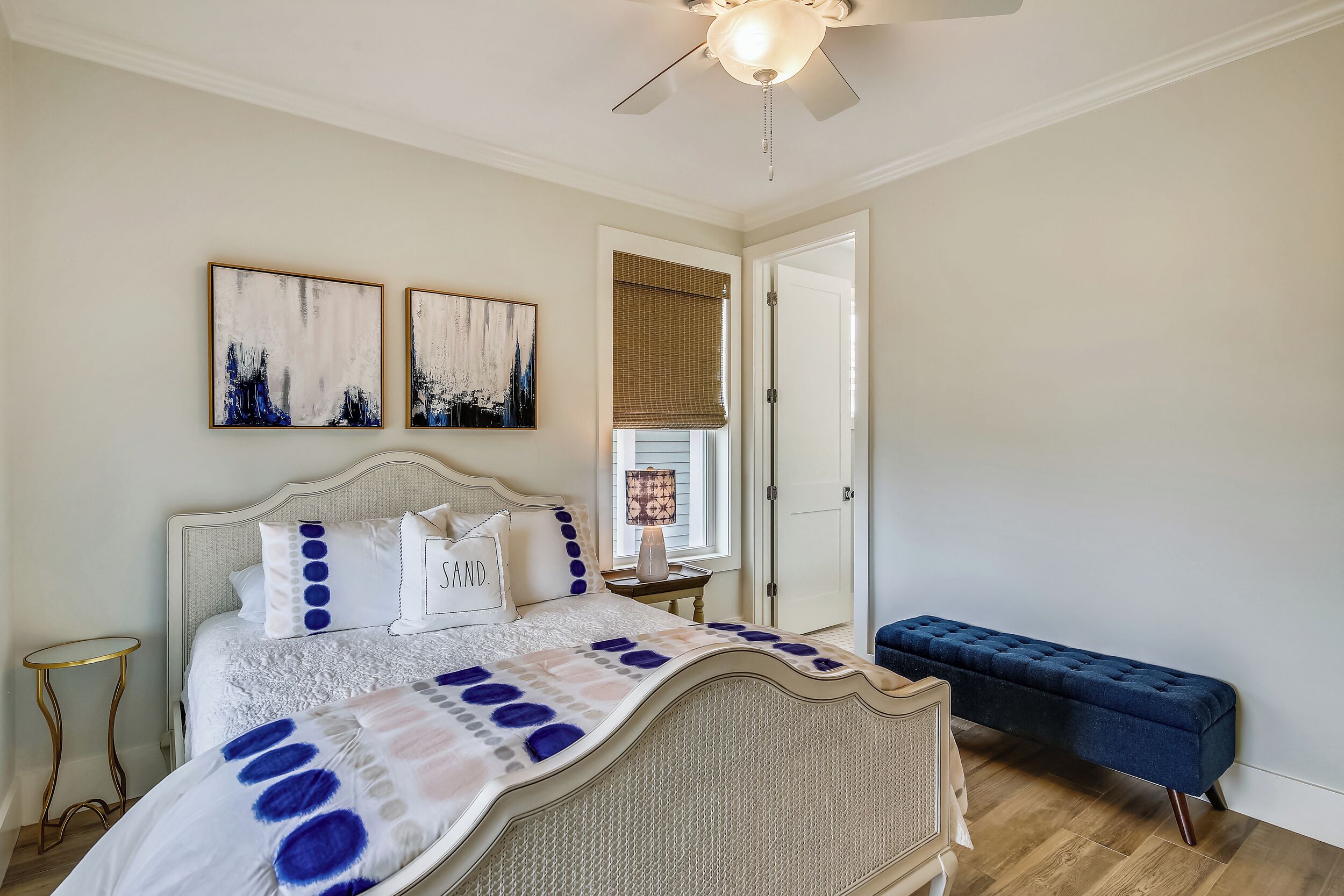 Un dormitorio con cama, un banco y obras de arte en la pared.