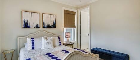 Un dormitorio con cama, un banco y obras de arte en la pared.