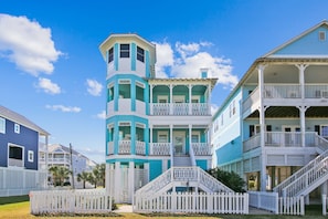 Stunning coastal building with a unique tower and balcony, surrounded by a white picket fence and staircase.
