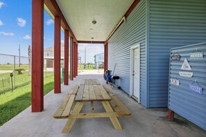 Enjoy a picnic in this outdoor space with a wooden table and shed, surrounded by a grassy field and trees.