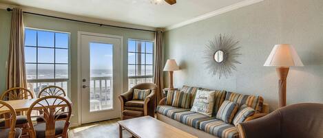 A living room with a ceiling fan, a sofa, a coffee table, and a dining area with chairs and a table.