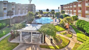 A pool area with a pergola, a view of the ocean, and a parking lot. - All for Fun by Ryson Vacation Rentals (Galveston)