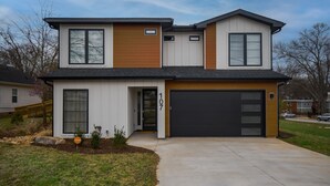 A two-story house with a garage, a front door, and a driveway.