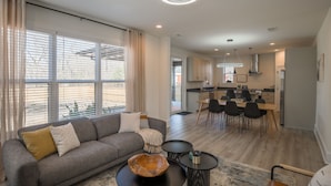 A modern living room with a sofa, coffee table, and dining area with chairs and a table.