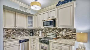 A kitchen with white cabinets, a microwave, a stove, and a dishwasher. - Ocean Oasis by Ryson Vacation Rentals (Galveston)