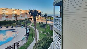 A hotel with a pool, palm trees, and a view of the ocean. - Ocean Oasis by Ryson Vacation Rentals (Galveston)