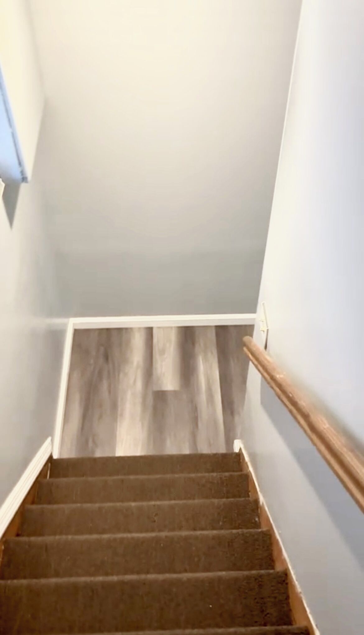 Un escalier avec des marches en bois et une rampe, menant à un palier doté d’un plancher en bois.