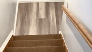 A staircase with wooden steps and a handrail, leading to a landing with a wooden floor.