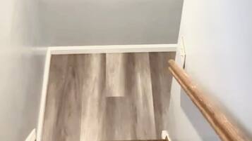 A staircase with wooden steps and a handrail, leading to a landing with a wooden floor.