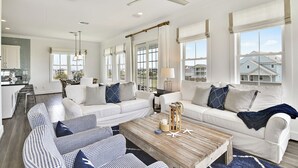 A spacious living room with a large wooden coffee table, white sofas, and blue patterned cushions.