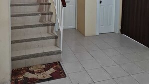Eine Treppe mit Handlauf, die zu einer Zwischenebene führt. Eine Fußmatte mit weihnachtlichem Motiv liegt am Fuß der Treppe.