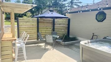 Relax in a shaded patio with a hot tub, seating area, and pergola.