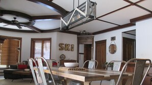 A dining area with a wooden table and metal chairs, a ceiling fan, and a wall-mounted light fixture.
