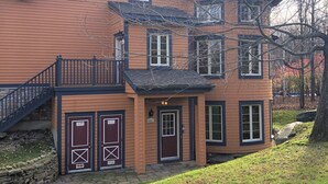 A two-story house with a brick exterior, a balcony, and a stone staircase leading to the entrance.
