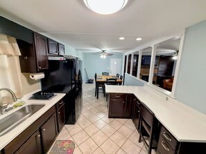A compact kitchen with a refrigerator, sink, and dining area.