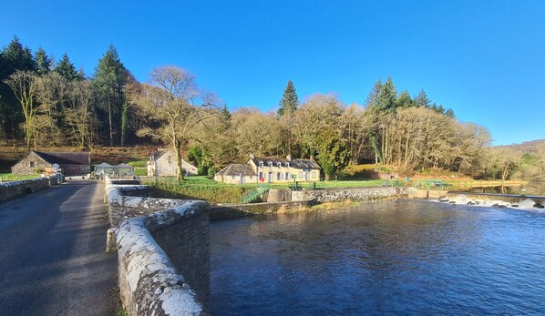 A stone bridge over a river, surrounded by trees and buildings.
