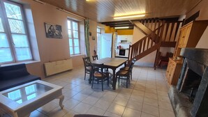 Un salón acogedor con chimenea, un comedor y una cocina al fondo.