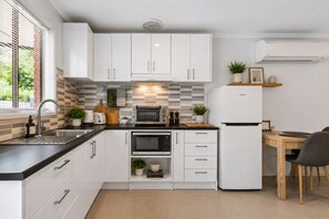 A modern kitchen with white cabinets, a built-in oven, a microwave, a toaster, and a refrigerator. - Golfside Getaway 2 by Ready Set Stay (Rosebud)