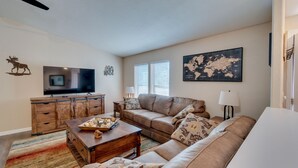 A living room with a television, wooden furniture, a world map, and a couch. - 3 Bed, 2 Bath Cabin in Munds Park AZ Close To Flagstaff and Sedona (Munds Park)