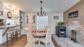 A modern kitchen with a dining area, a fireplace, and a clock on the wall. - 3 Bed, 2 Bath Cabin in Munds Park AZ Close To Flagstaff and Sedona (Munds Park)