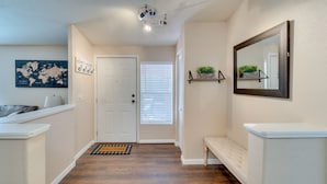 A hallway with a white door, a world map, a welcome mat, a bench, a mirror, and a ceiling light fixture. - 3 Bed, 2 Bath Cabin in Munds Park AZ Close To Flagstaff and Sedona (Munds Park)