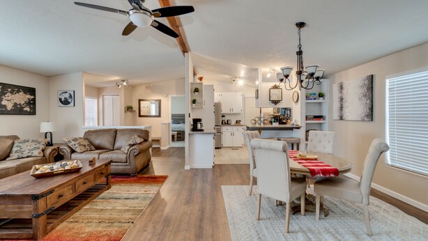 A spacious living room with a sofa set, a dining area with a table and chairs, a kitchen in the background, and a ceiling fan. - 3 Bed, 2 Bath Cabin in Munds Park AZ Close To Flagstaff and Sedona (Munds Park)