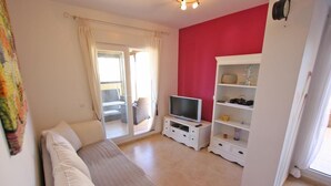 Una habitación con cama, televisión, un armario blanco y una pared roja.