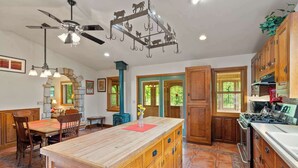 A spacious kitchen with wooden cabinets, a central island, and a stove. - 5 Acres in Ellison Bay! The Goddess Door Family Home (Ellison Bay)