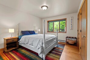 A bedroom with a bed, bedside tables, a window with a view, a door, and a wall-mounted artwork. - 5 Acres in Ellison Bay! The Goddess Door Family Home (Ellison Bay)