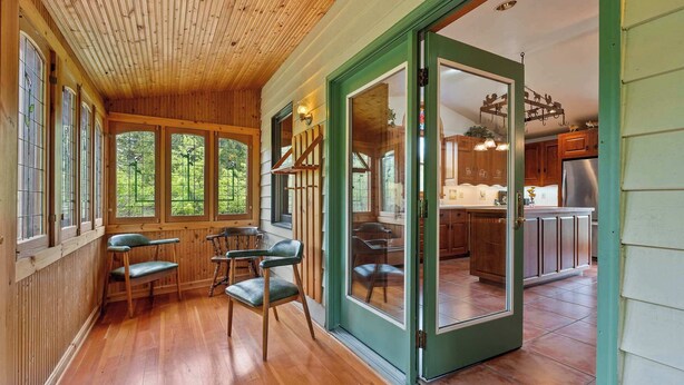 A wooden interior with a dining area, a kitchen, and a sliding glass door leading to an outdoor area. - 5 Acres in Ellison Bay! The Goddess Door Family Home (Ellison Bay)