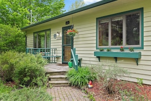A house with a porch, a green door, and a window with a flower box.