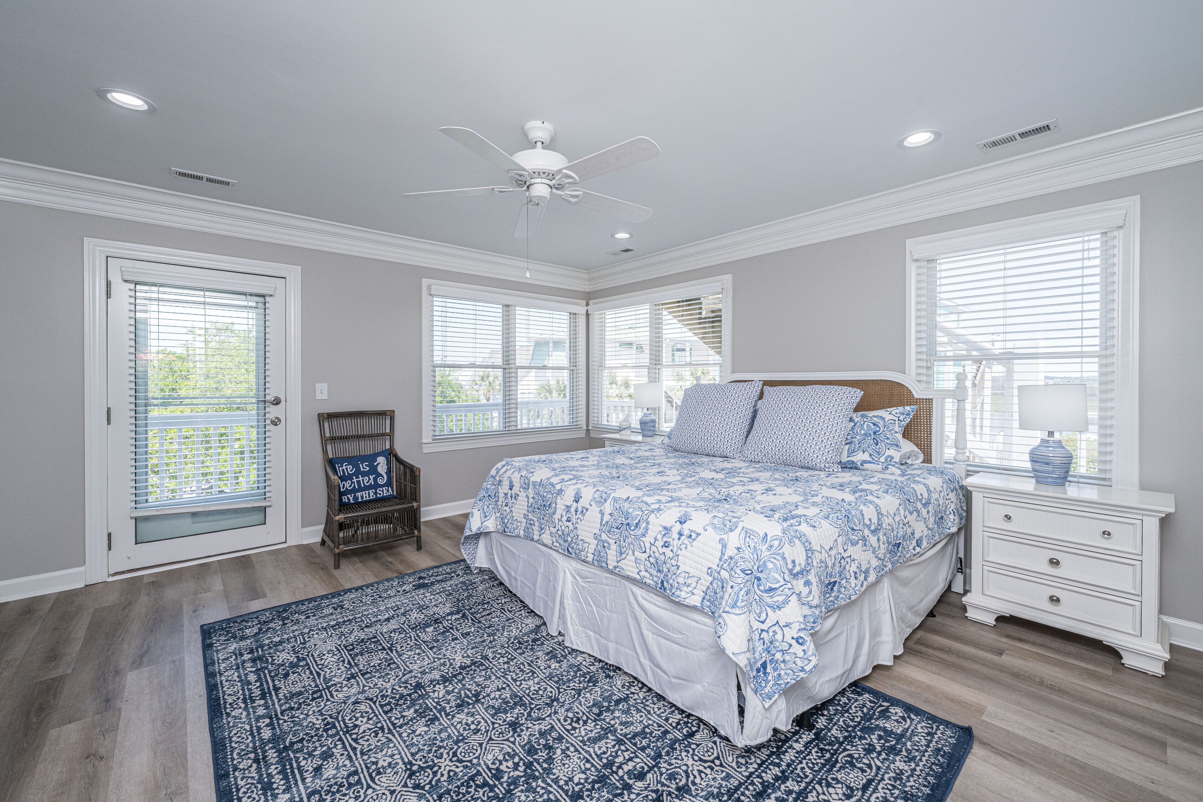 A bedroom with a large bed, a ceiling fan, and a window with blinds.