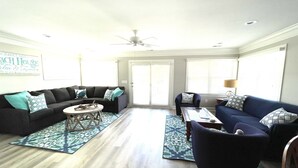 A spacious living room with a sectional sofa, a round coffee table, and a blue armchair. - DEEP WATER Newly Renovated Waterfront Home-Wren's Nest (Edisto Island)