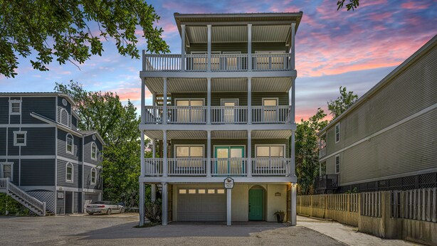 A multi-story building with a balcony on the second floor, a garage, and a green door. - DEEP WATER Newly Renovated Waterfront Home-Wren's Nest (Edisto Island)