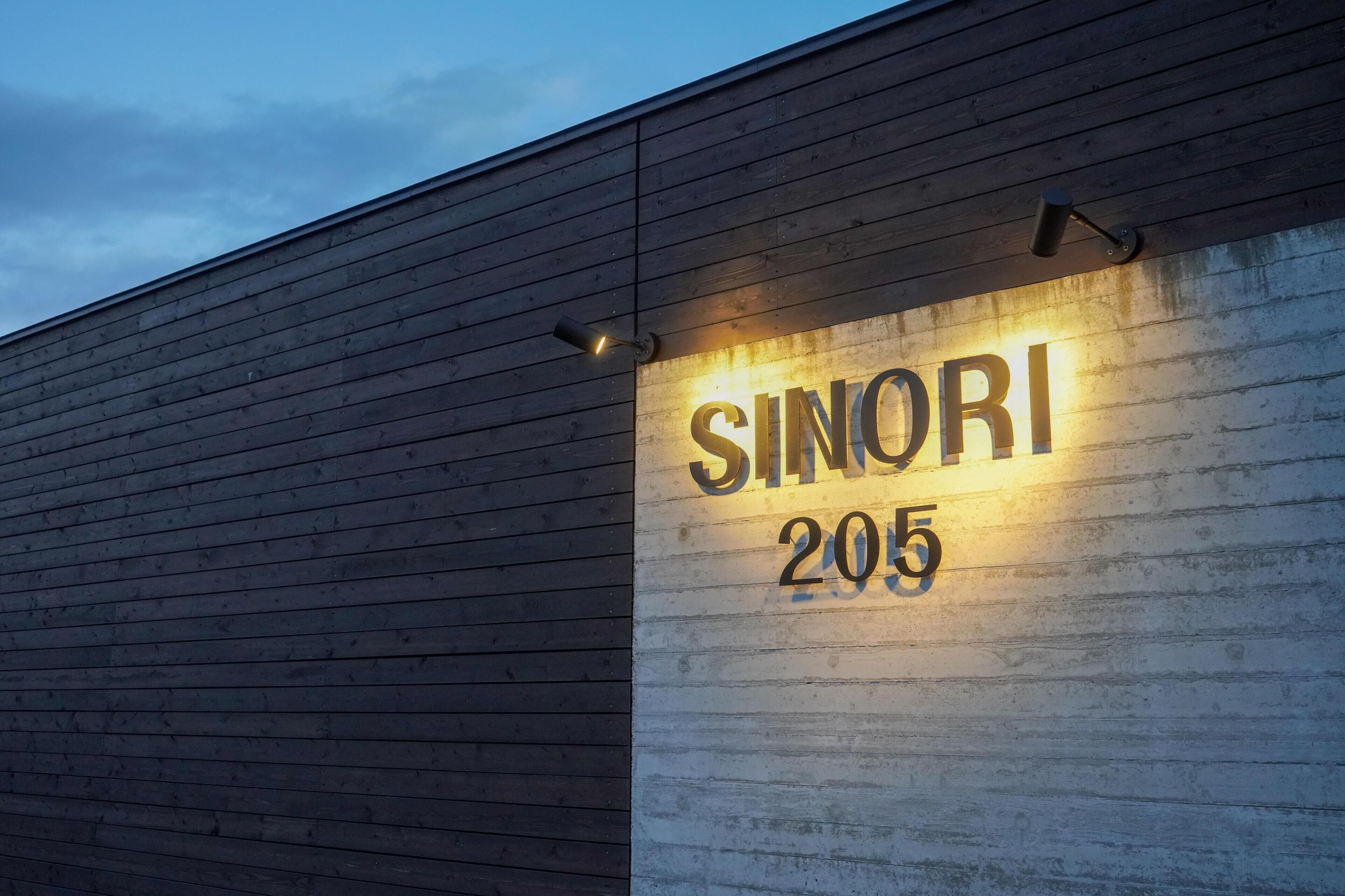 A building with a wooden exterior and a sign that reads "SINORI 205".