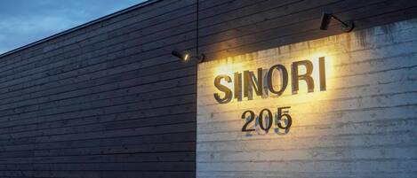 A building with a wooden exterior and a sign that reads "SINORI 205".