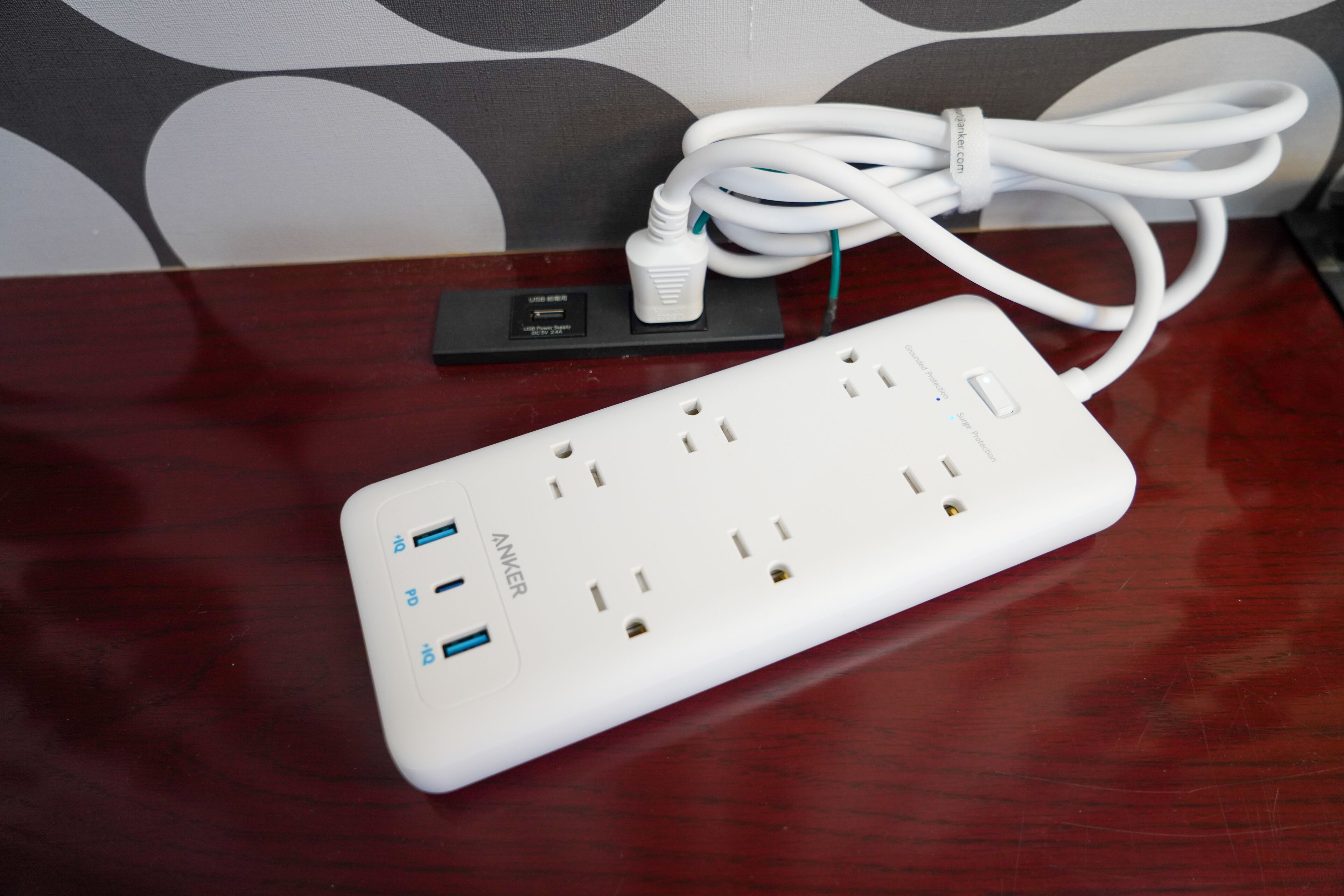 A white power strip with multiple USB ports and a standard electrical outlet on a wooden surface.