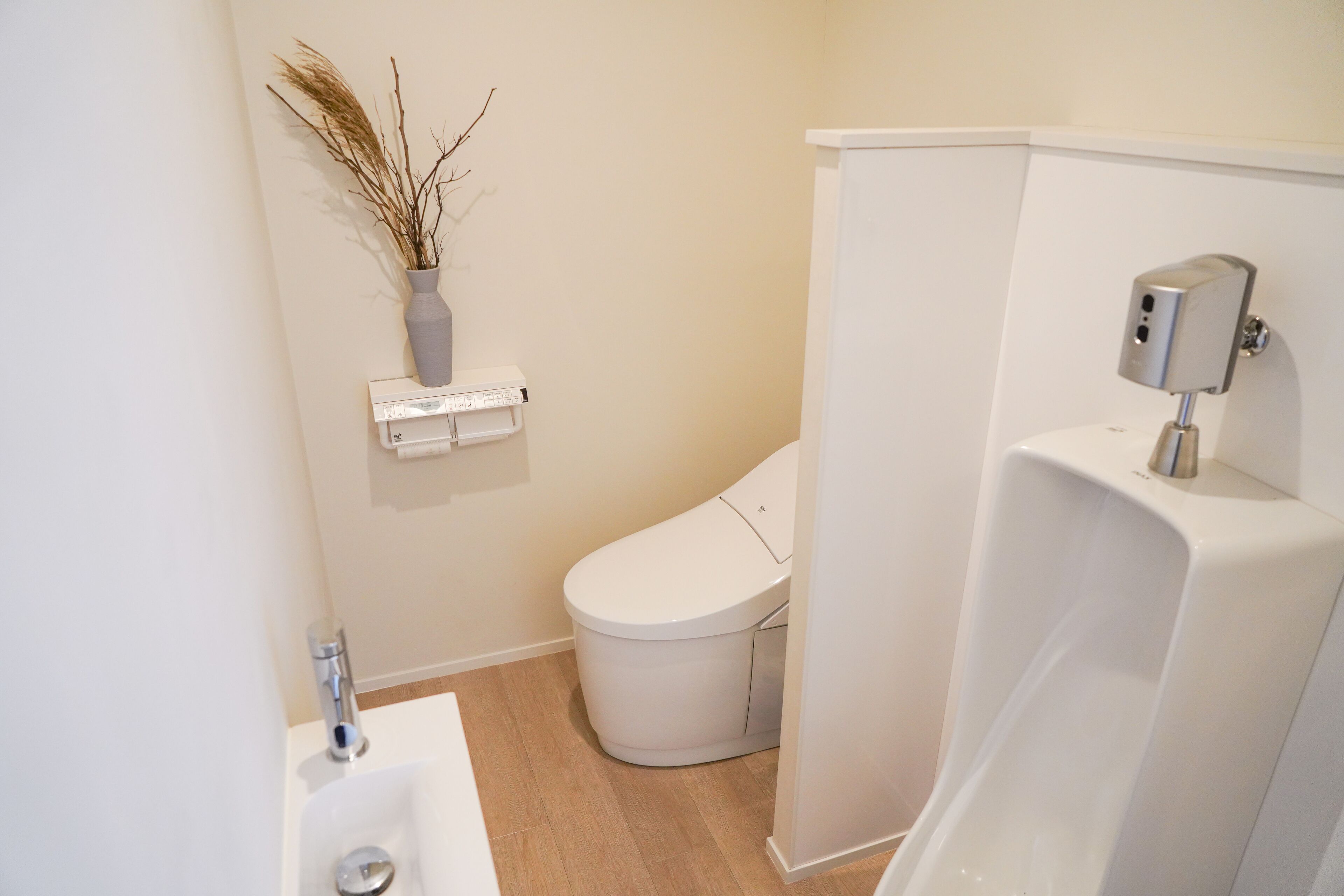 A modern bathroom with a toilet, sink, and a wall-mounted soap dispenser.
