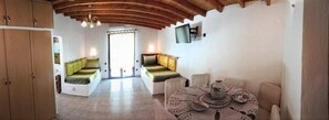 Relax in this spacious room with a high ceiling, featuring a seating area with a cushioned bench and a small table.