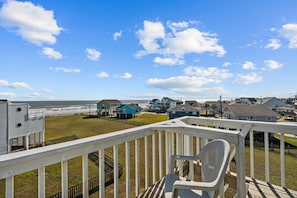 A deck with a view of houses and the ocean.