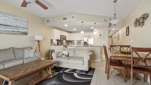 A modern living room with a sofa, coffee table, and dining area with chairs.