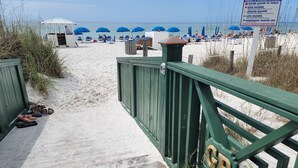 A beach walkway leading to a beach area with umbrellas and beach chairs. - Grand Panama Resort beautiful condo (Panama City Beach)