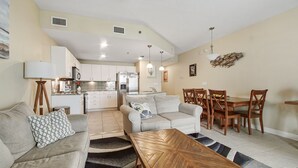 A modern living room with a sofa, coffee table, and dining area. - Grand Panama Resort beautiful condo (Panama City Beach)
