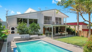 A modern two-story house with a swimming pool, large windows, and a covered patio area. - Laze @ Lighthouse - modern family home with views and pool (Port Macquarie)