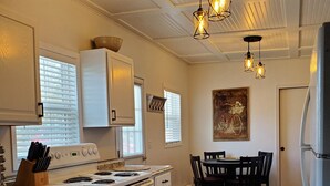 A kitchen with white cabinets, a stove, and a dining area with a table and chairs.