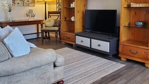 A living room with a sofa, TV, wooden shelving, and a lamp.