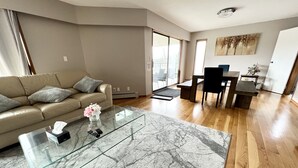 A modern living room with a glass coffee table, a sofa, and a dining area with chairs and a table. - 💫🏡6 bedroom/3.5 bath home private acreage parkings (Mission)