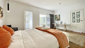 Un dormitorio moderno con una cama grande, un escritorio y una puerta con diseño de hojas.
