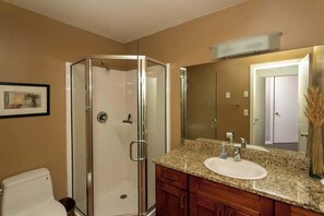 A bathroom with a glass-enclosed shower, a sink with a mirror, and wooden cabinets.